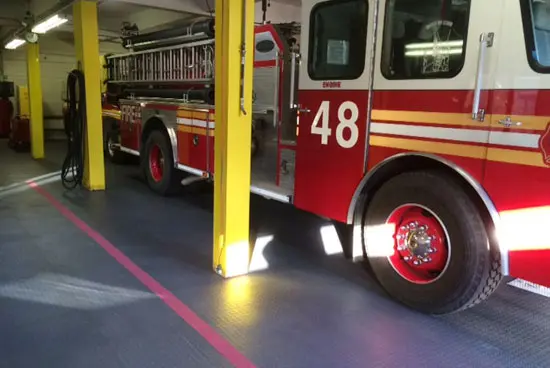 A fire truck parked in the garage of a firehouse.