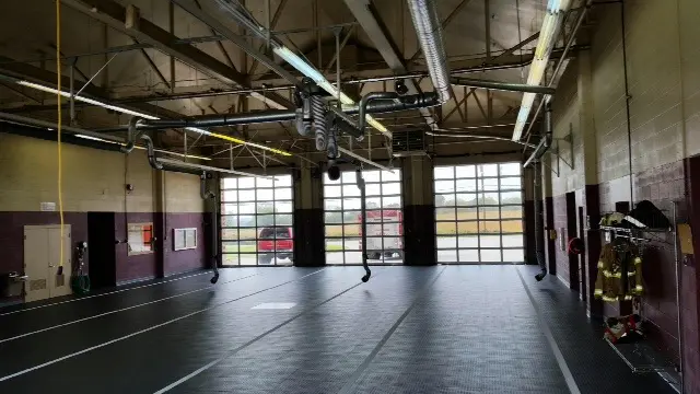 A large room with two windows and a truck parked in it.