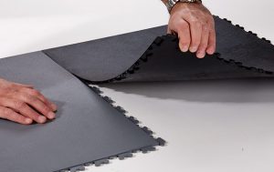 A person is cutting the black mat on top of it.