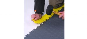 A person using a hammer to cut the floor.