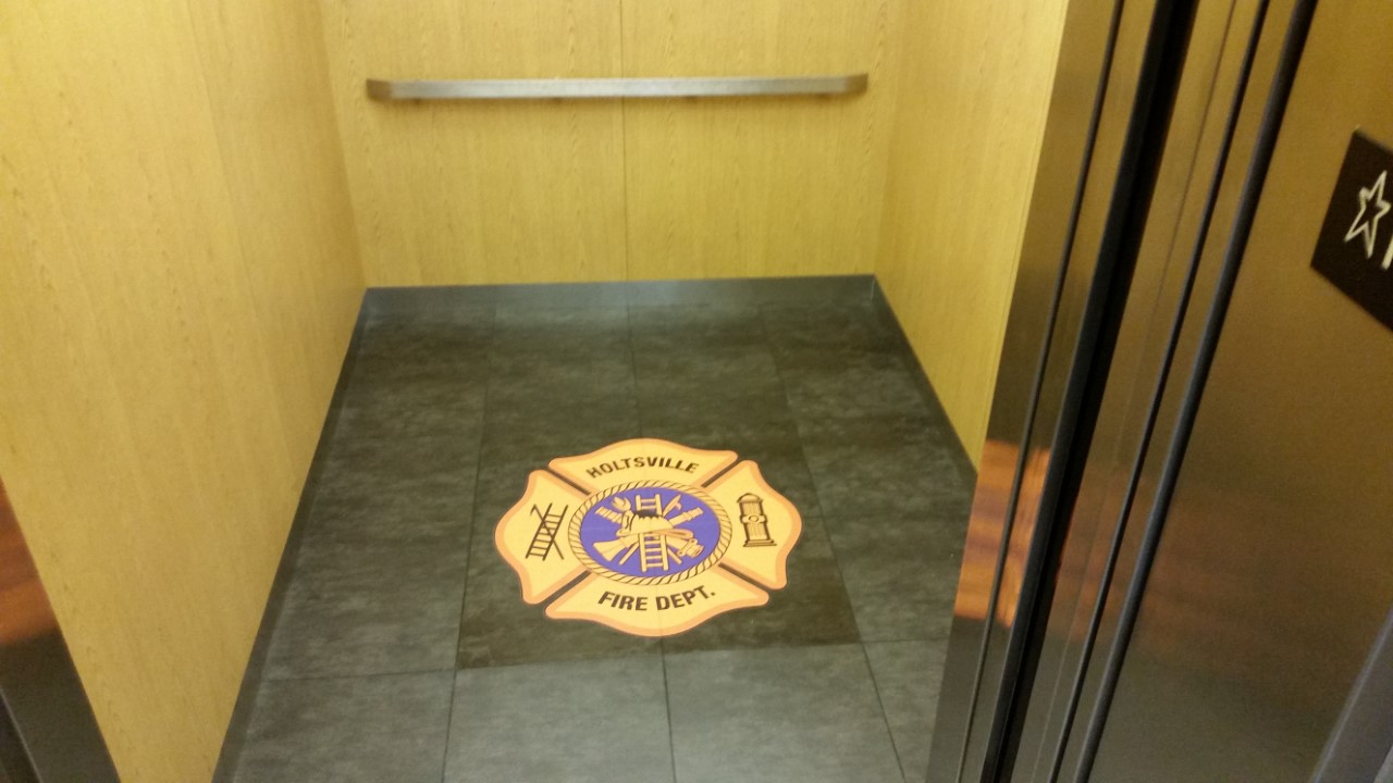 A fire department logo is painted on the floor of an elevator.